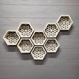 8 of the hexagon distressed white shelves all together on a greyish white paneled wall there is on shelf on the left, two next to that, two lower next to that then two next to that same eight as the second set and the last shelf is at the top side of the top shelf