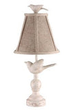 a cream colored lamp base with a bird and a bird finial at the time of the tan shade